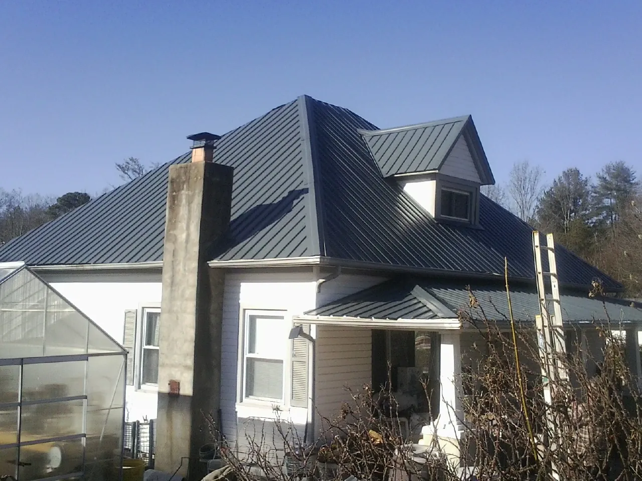 Dark blue standing seam metal roof on a white farmhouse with dormer — Slate & Tile Roof Repair by Roofing Brothers in Hamtramck