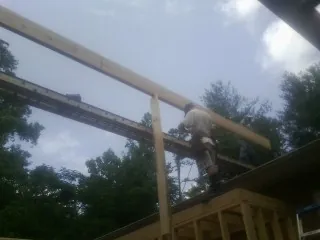 Carpenter setting a ridge beam over a new addition frame — Ice Dam Removal by Roofing Brothers in Hamtramck