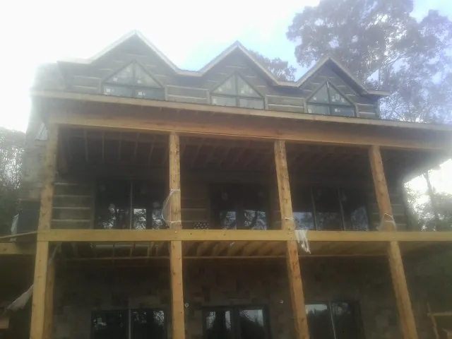 Dormers and porch framing on a large log home under construction — Roof Coating work by our crew in Hamtramck