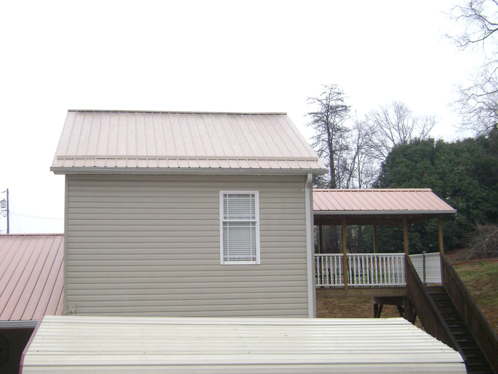Tan metal roofs on a two story addition and attached porch, from a Roof Replacement job in Hamtramck